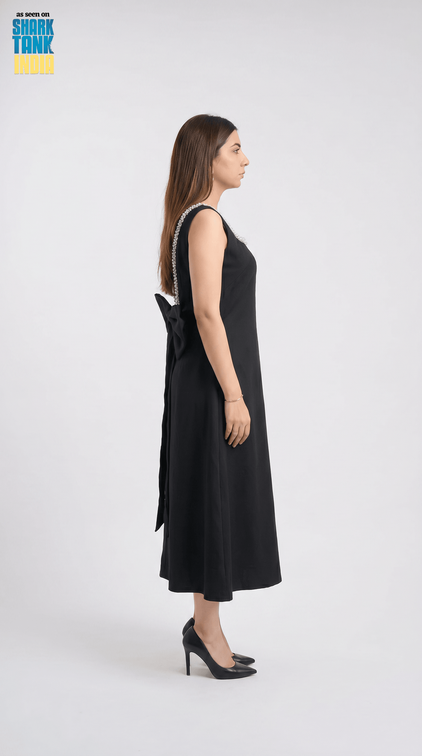 Woman wearing a black dress with a bow detail on a white background