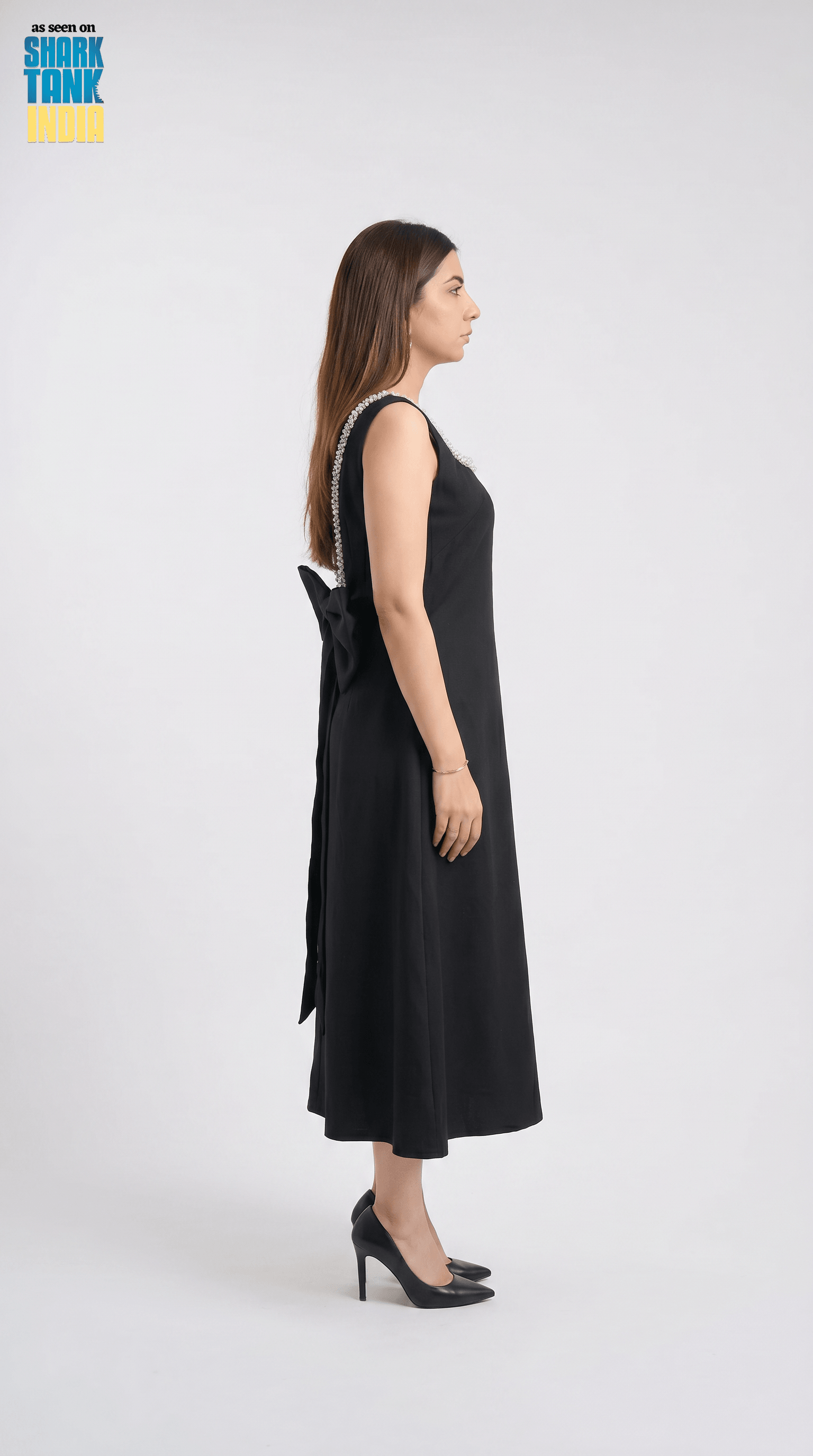 Woman wearing a black dress with a bow detail on a white background