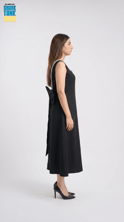 Woman wearing a black dress with a bow detail on a white background