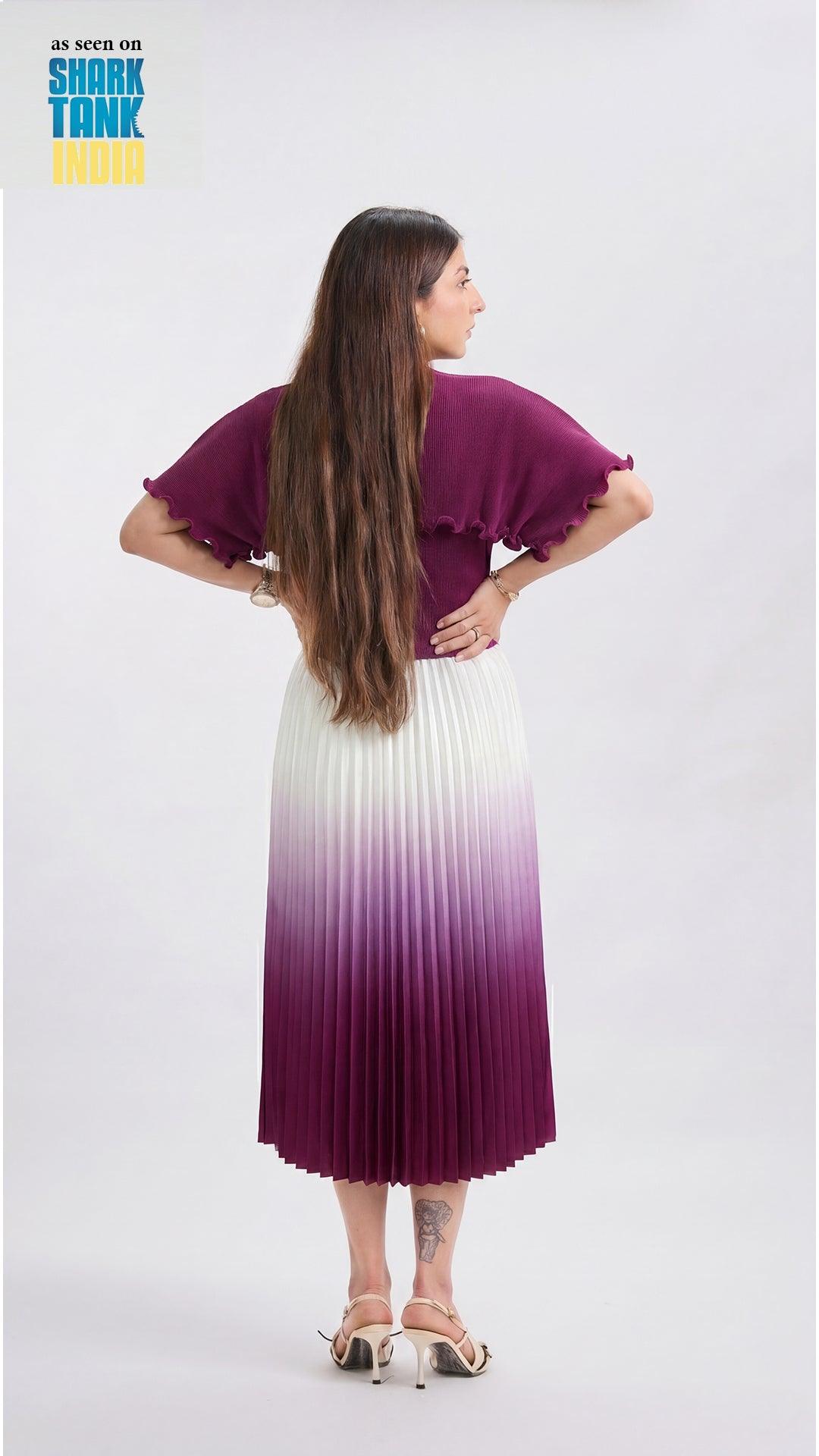 Woman wearing a purple and white dress with a gradient effect, standing against a plain background.