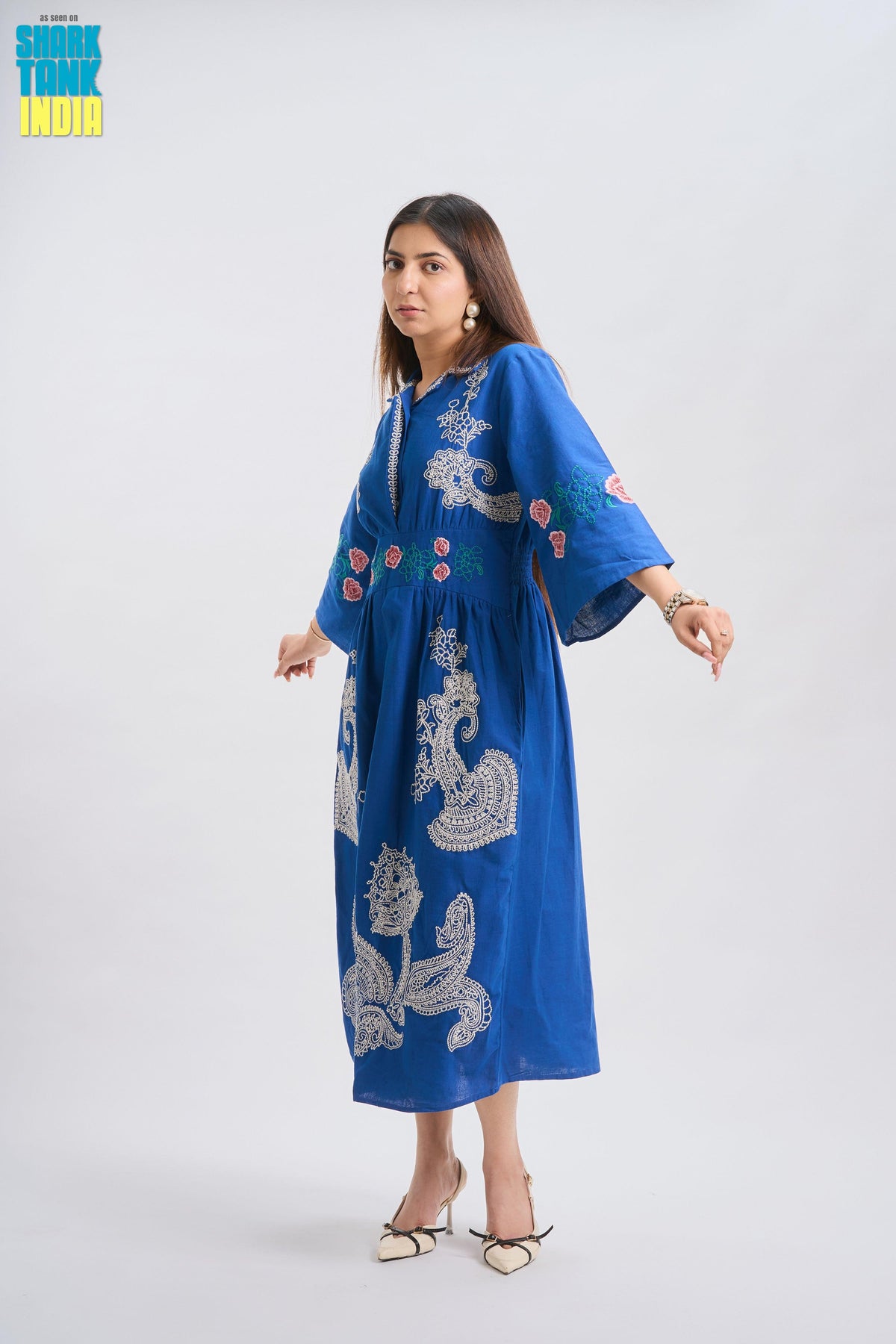 Woman wearing a blue embroidered dress on a white background