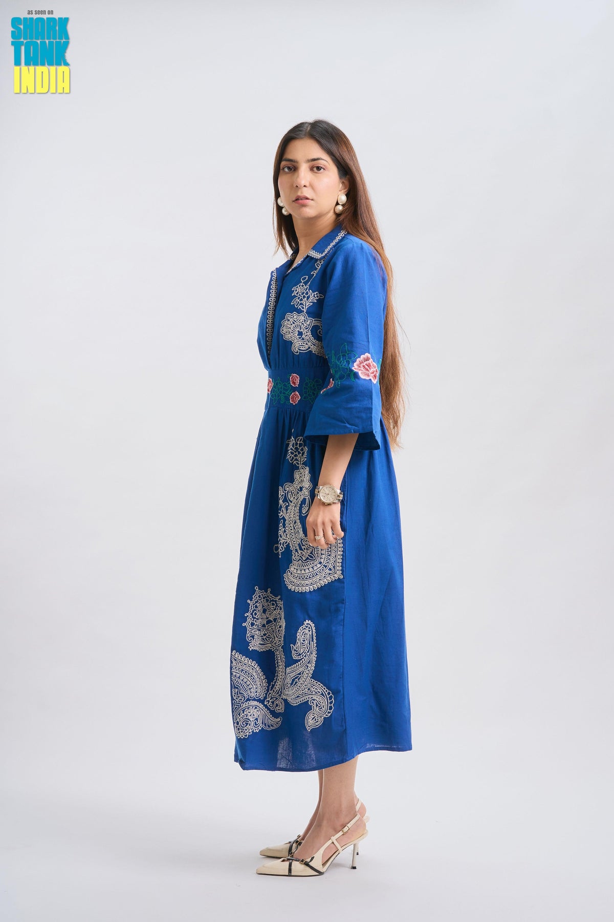 Woman wearing a blue embroidered dress on a white background