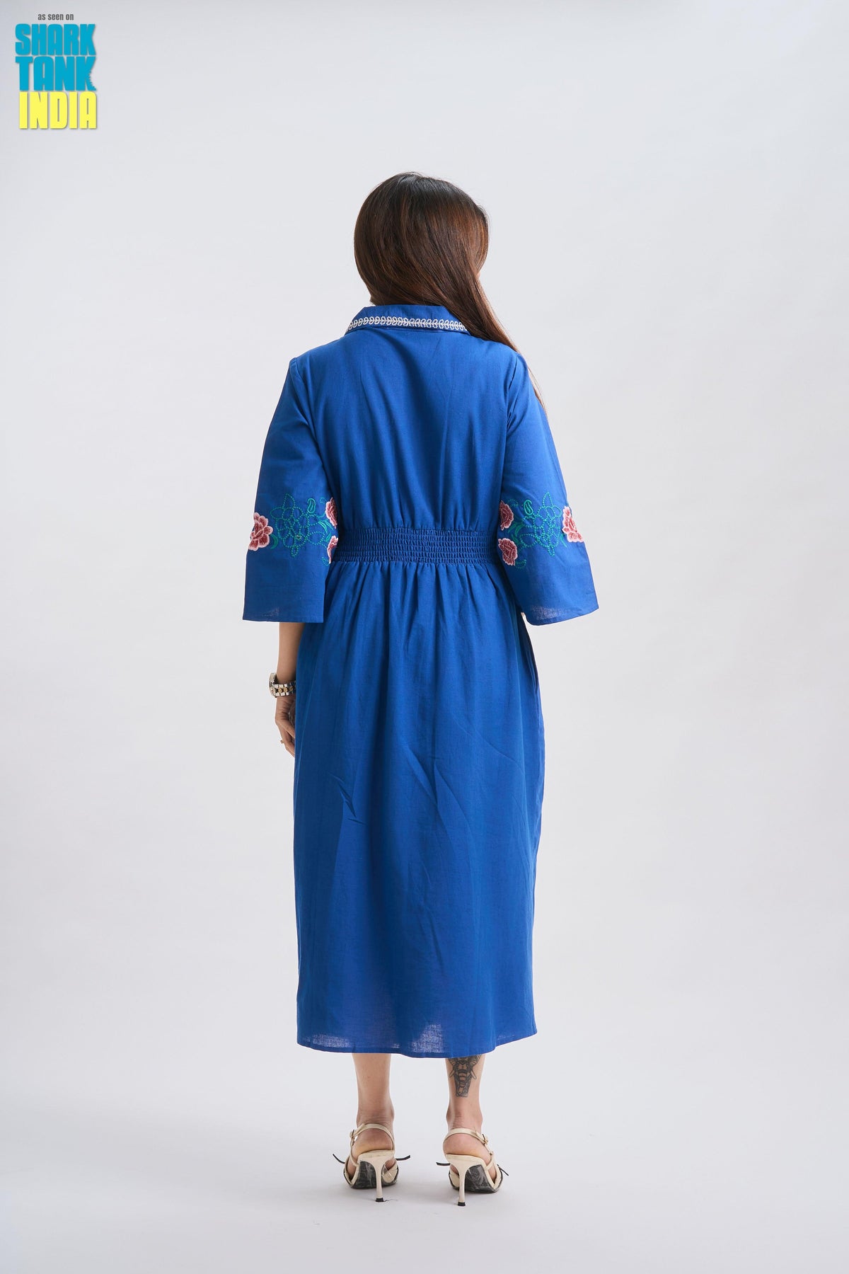 Woman wearing a blue dress with floral patterns on a white background