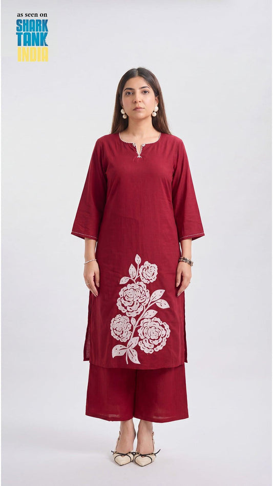 Woman wearing a maroon kurta with white floral embroidery on a white background