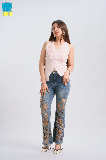 Woman wearing a pink sleeveless top and blue jeans with floral designs on a white background