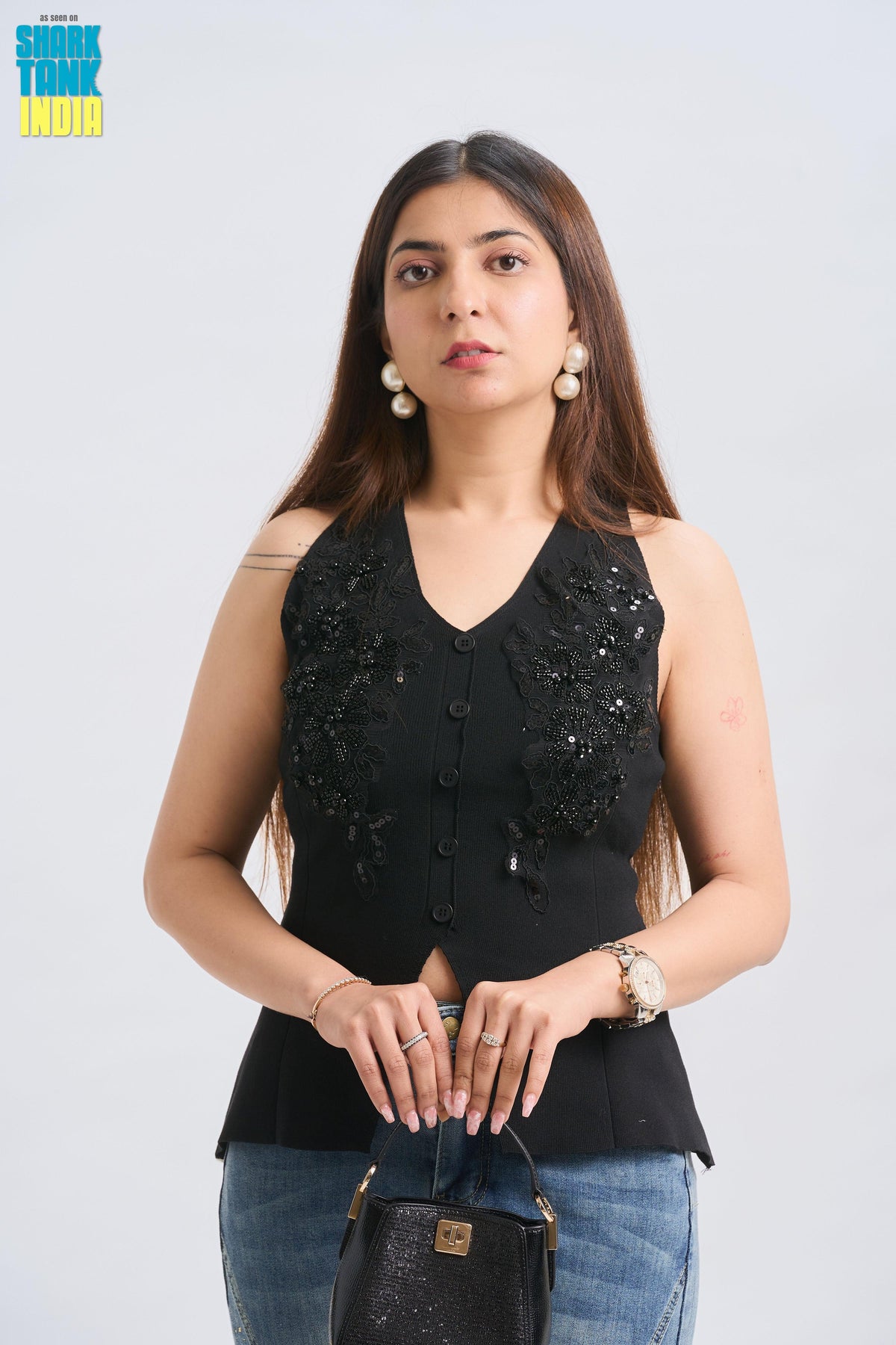 Woman wearing a black sleeveless top with sequins on a white background