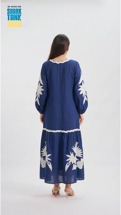 Woman wearing a blue dress with white floral patterns on a white background