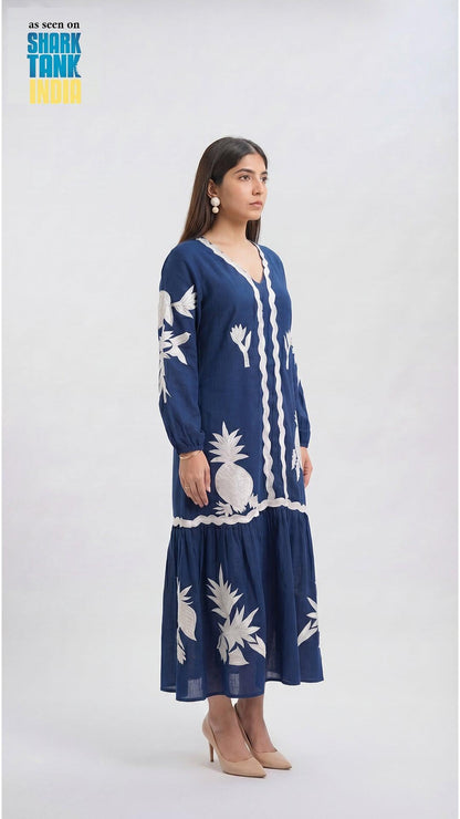 Woman wearing a navy blue dress with white pineapple patterns on a white background