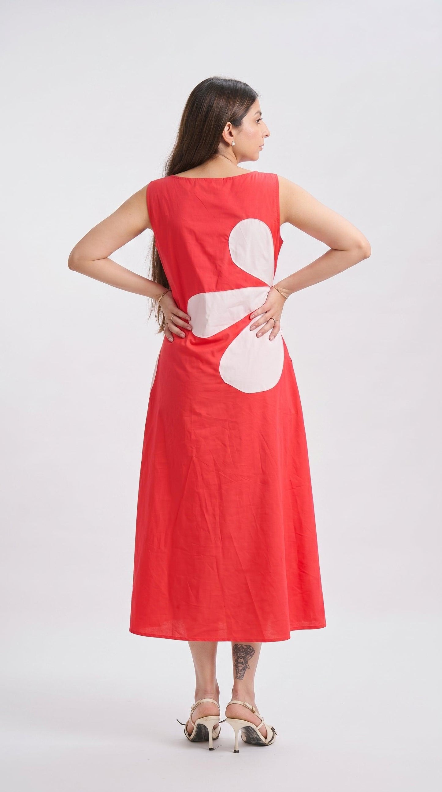 Woman wearing a red dress with a white abstract design on a plain background