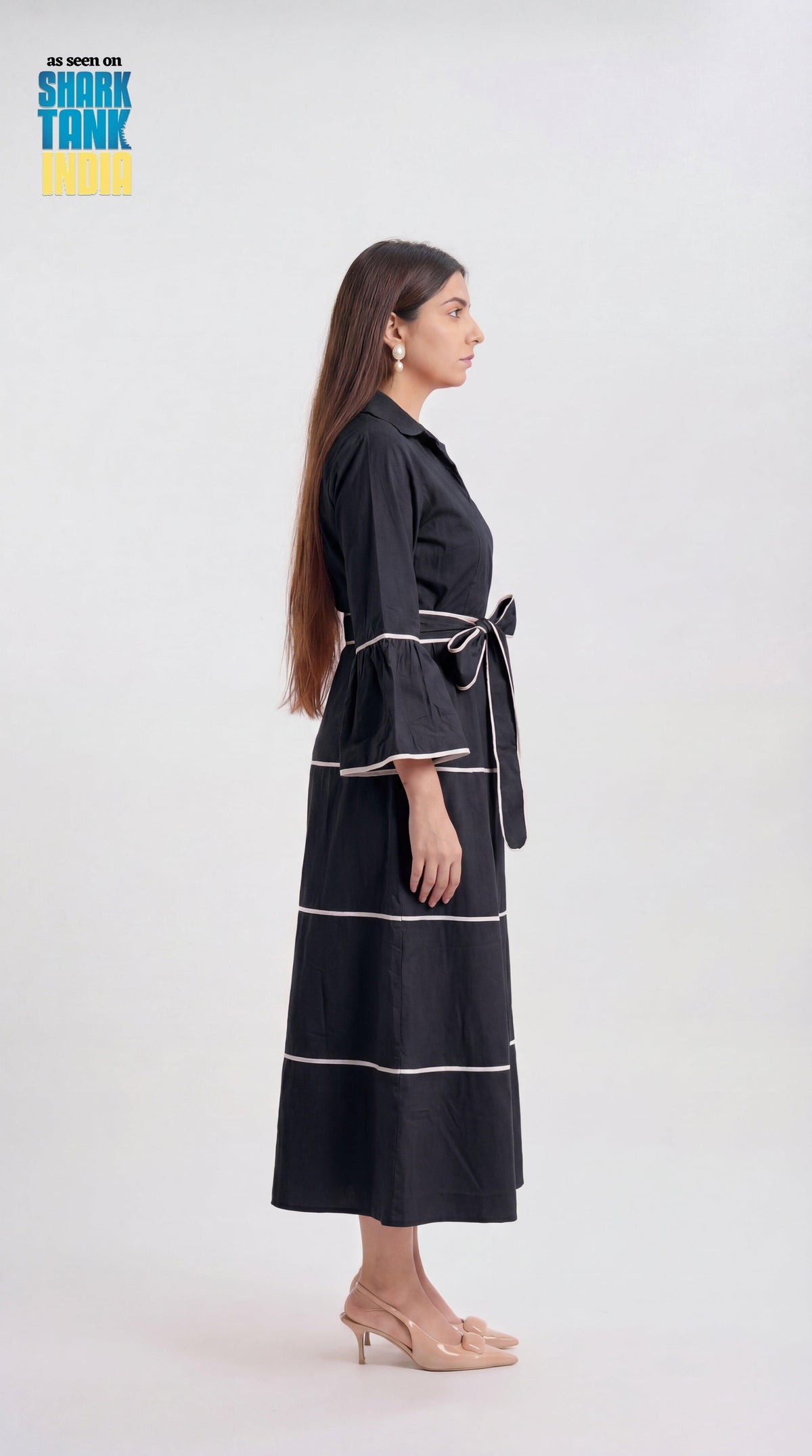 Woman wearing a black dress with white stripes on a white background
