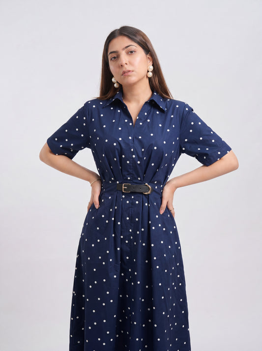 Woman wearing a navy blue dress with white polka dots on a light gray background