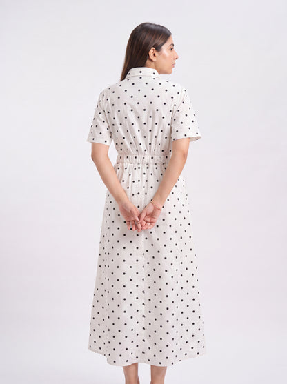 Woman wearing a white dress with black polka dots on a white background