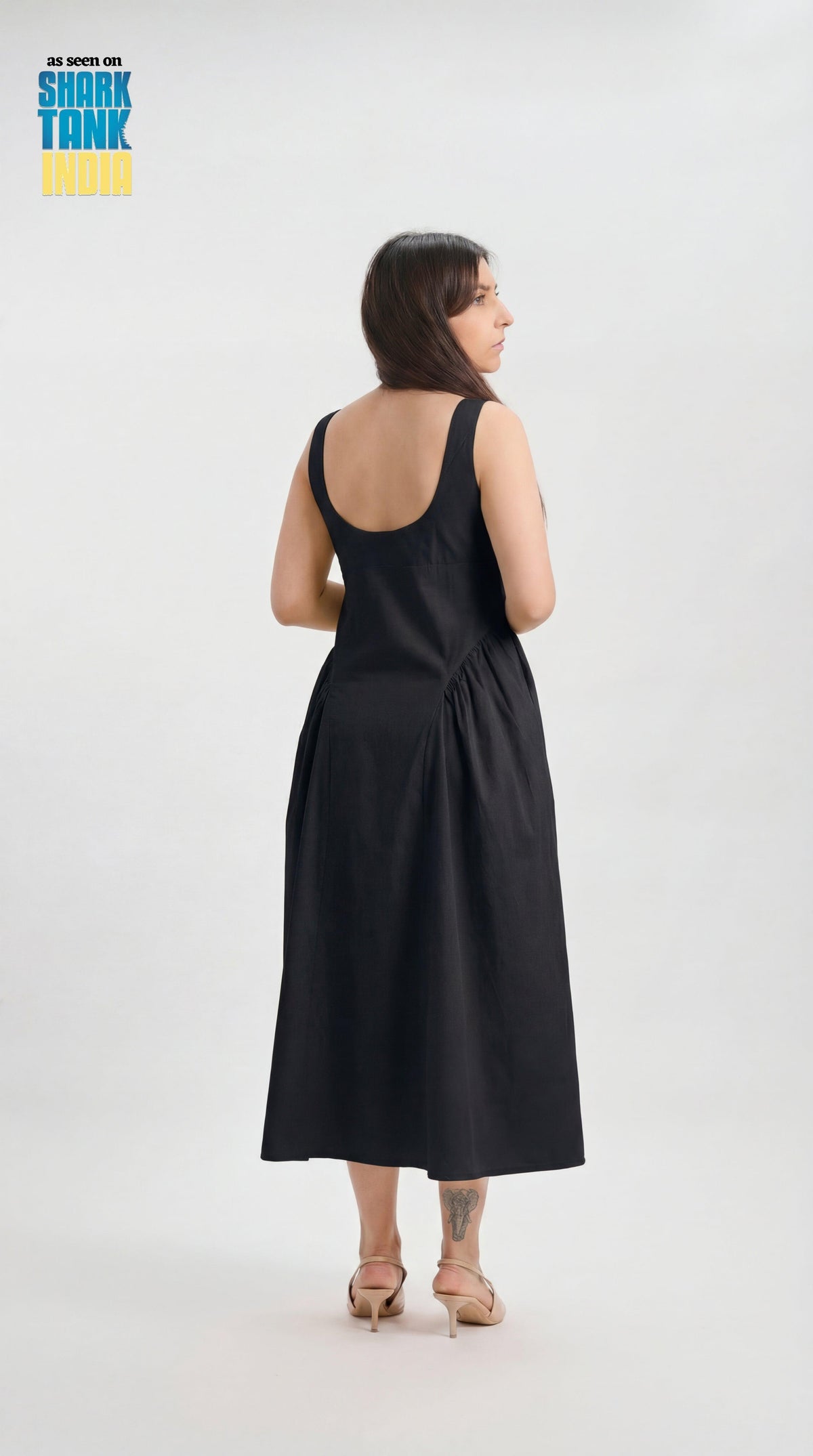 Woman wearing a black sleeveless dress on a white background with 'Shark Tank' branding.