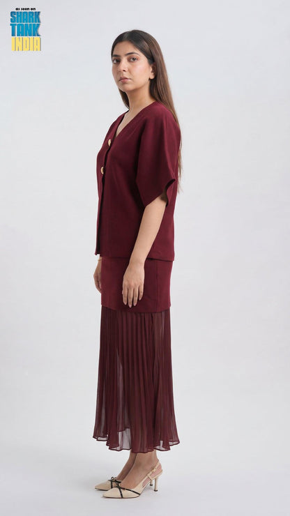 Woman wearing a burgundy outfit with a sheer overlay on a white background