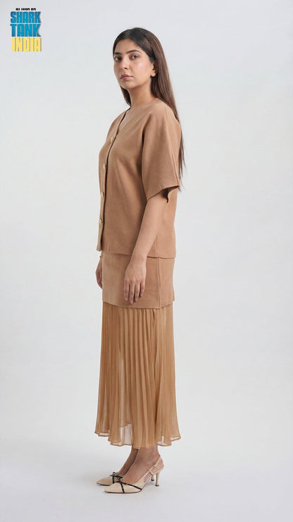 Woman wearing a beige outfit with a pleated skirt on a white background