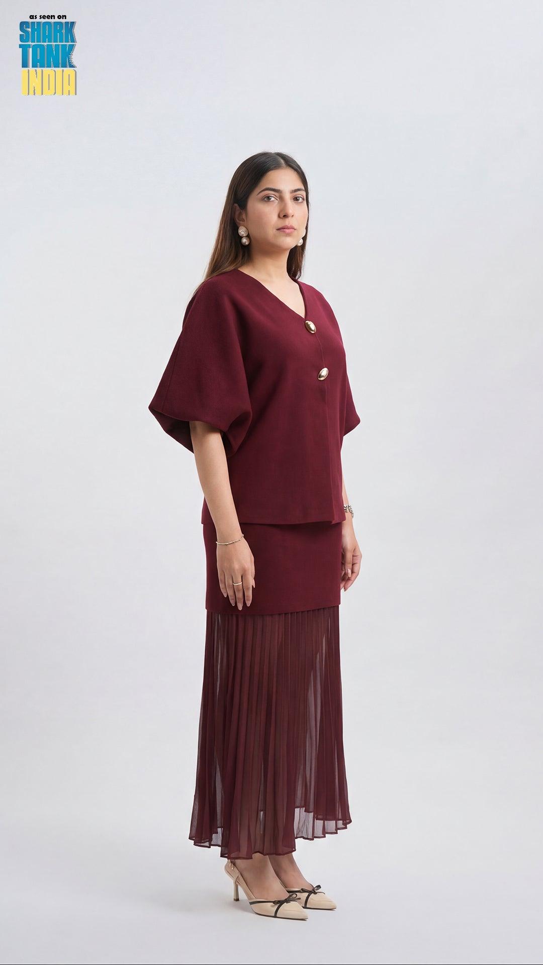 Woman wearing a burgundy outfit with a top and pleated skirt on a white background
