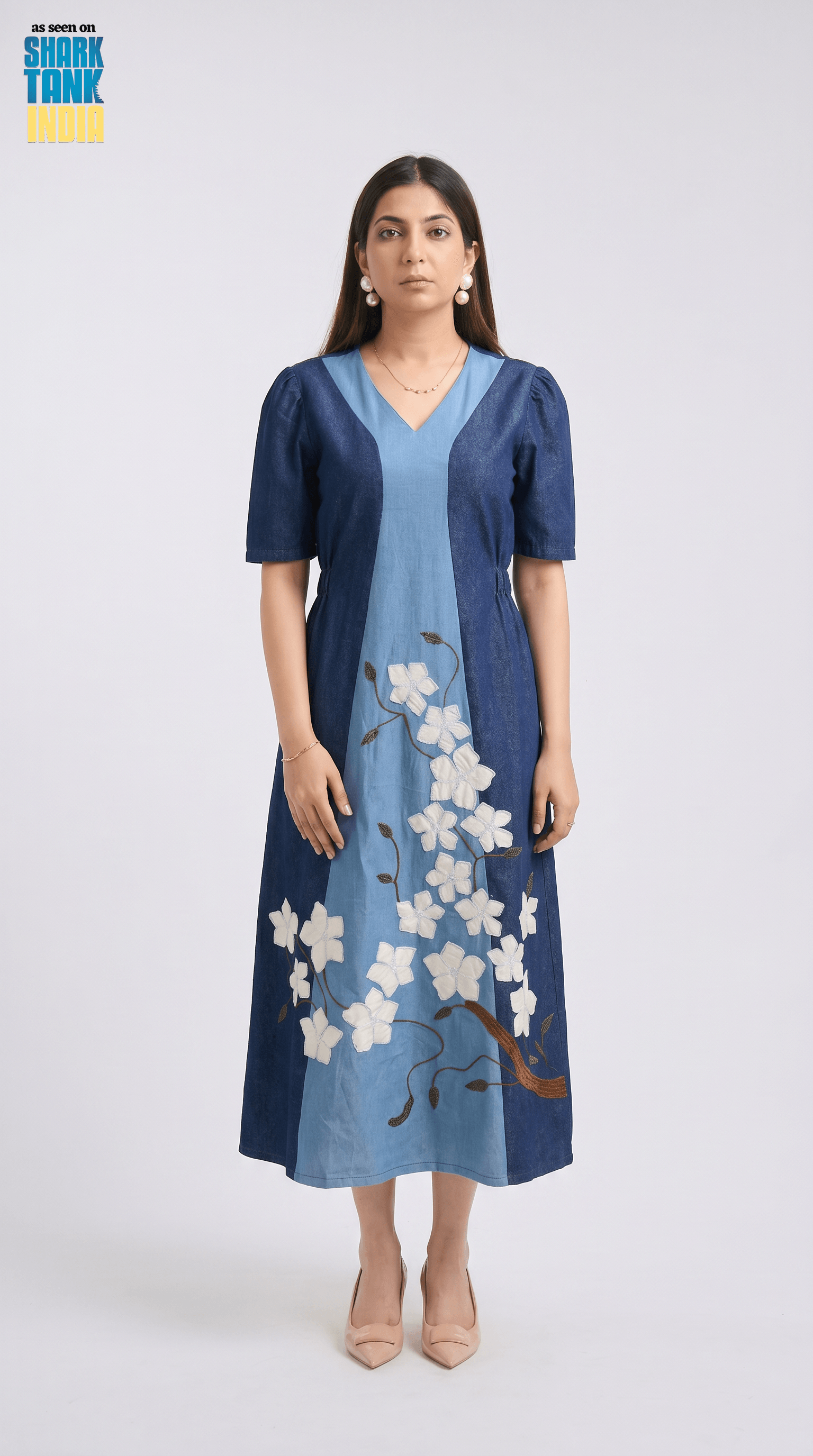 Woman wearing a blue dress with floral embroidery on a white background