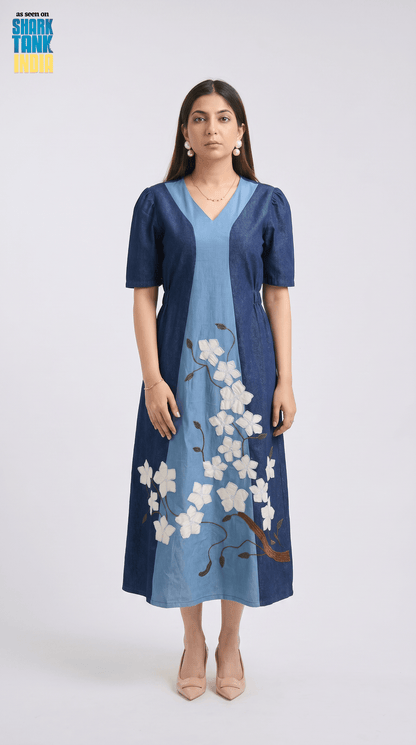 Woman wearing a blue dress with floral embroidery on a white background