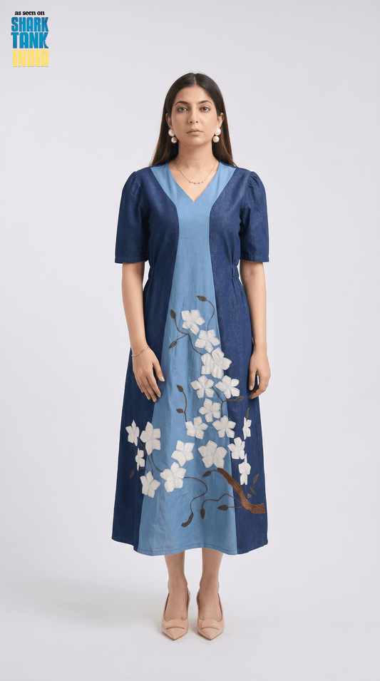 Woman wearing a blue dress with floral embroidery on a white background