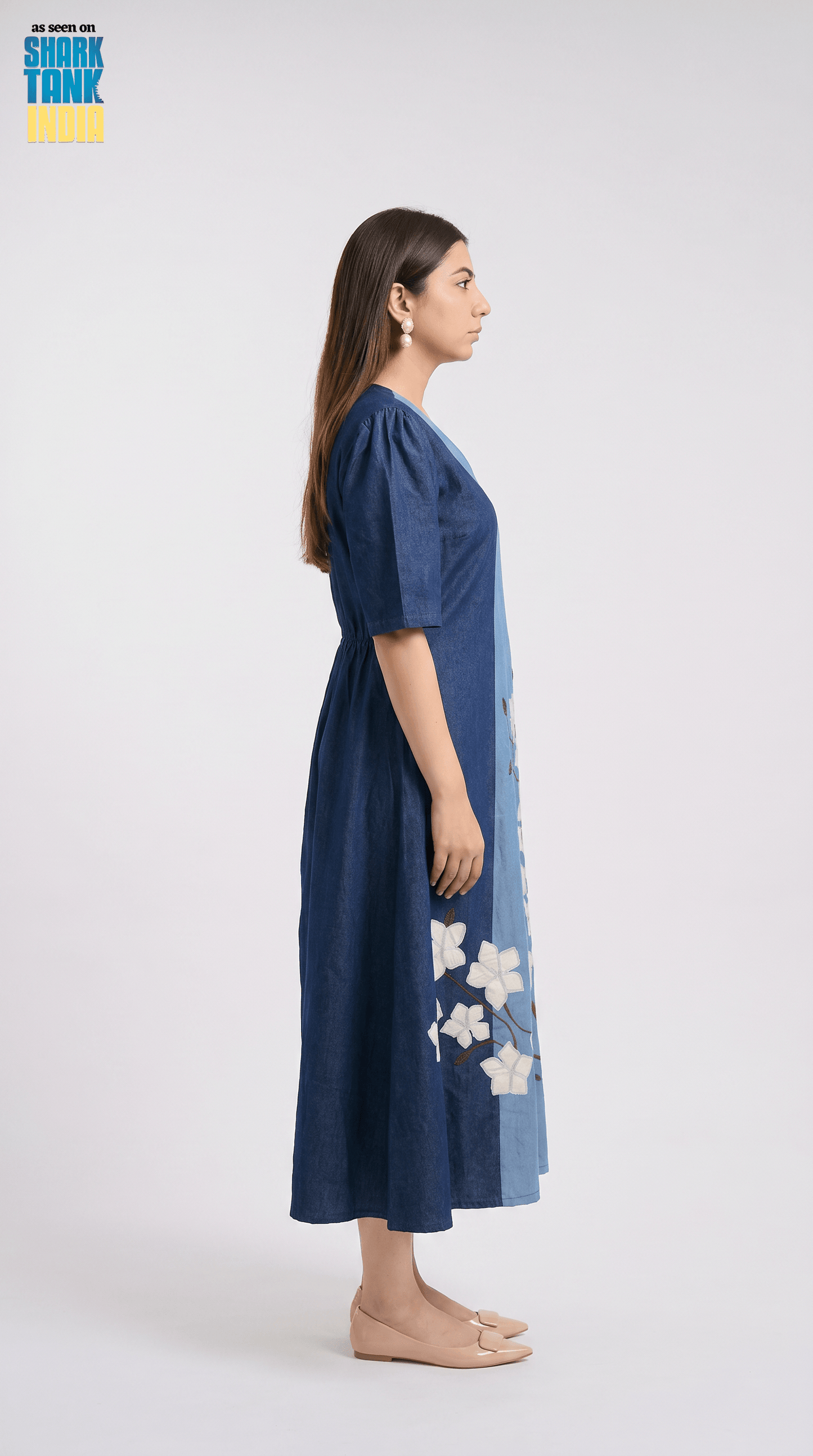 Woman wearing a blue dress with floral patterns on a white background