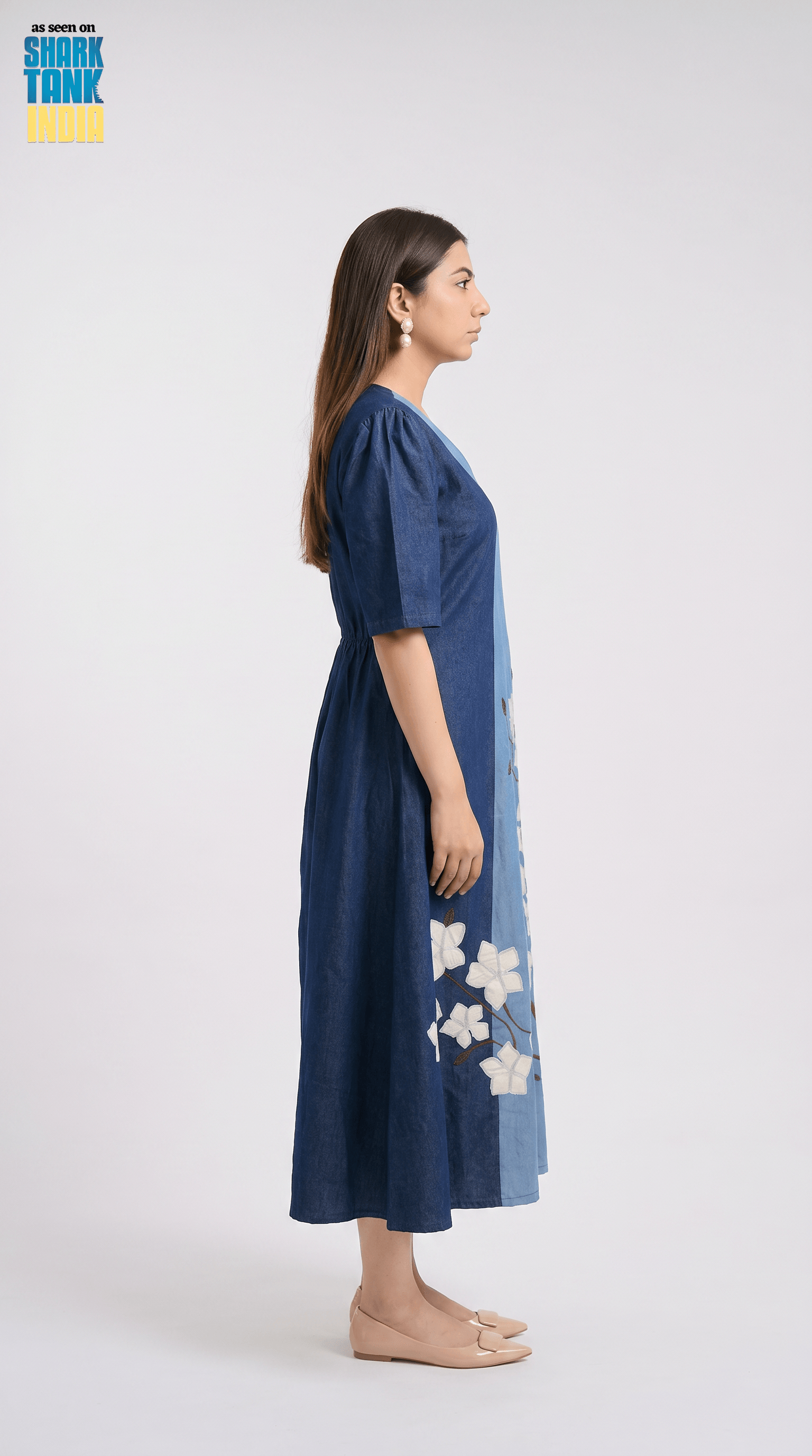 Woman wearing a blue dress with floral patterns on a white background