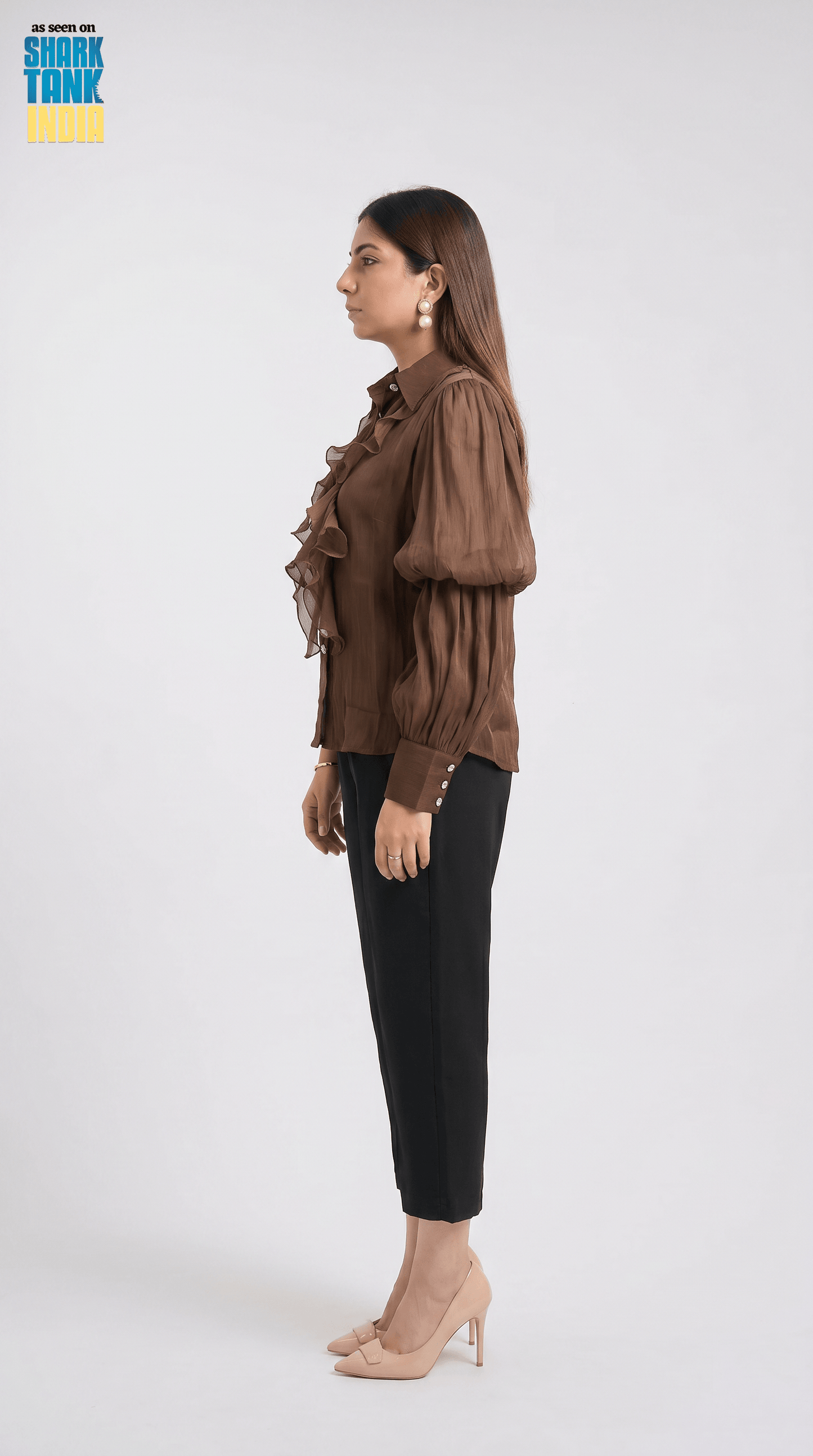 Woman wearing a brown blouse and black pants on a white background