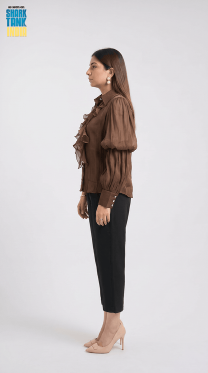 Woman wearing a brown blouse and black pants on a white background