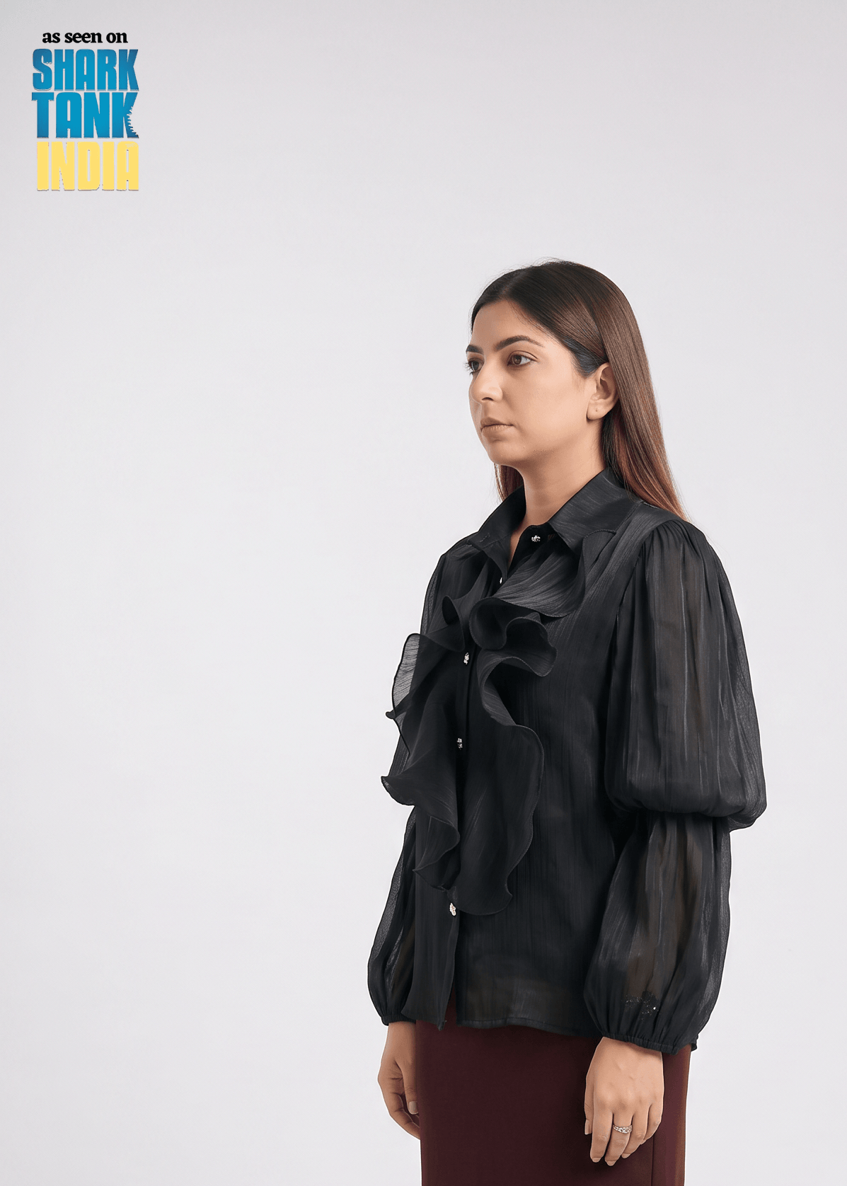 Woman wearing a black sheer blouse with puffed sleeves on a white background