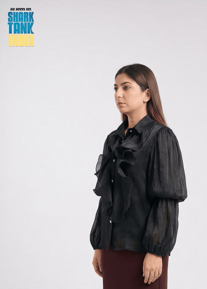 Woman wearing a black sheer blouse with puffed sleeves on a white background