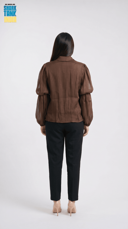 Person wearing a brown jacket and black pants on a white background