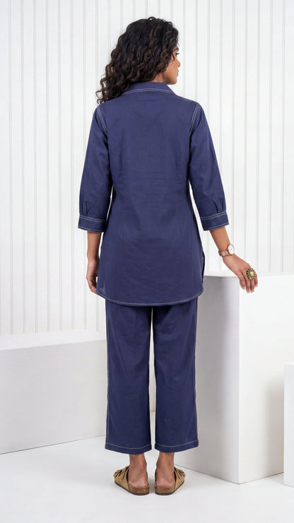 Woman wearing a navy blue outfit standing against a white background
