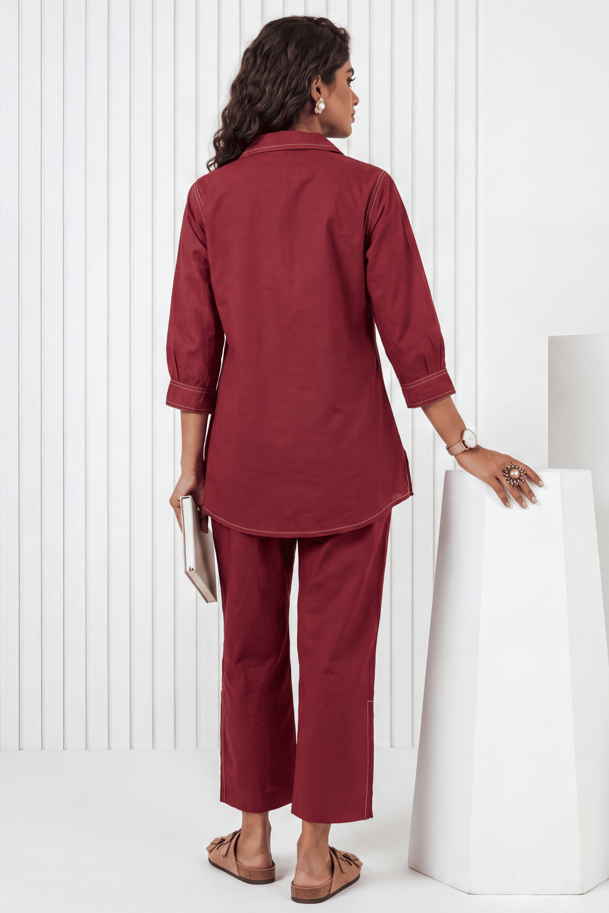 Woman wearing a maroon outfit standing against a white background