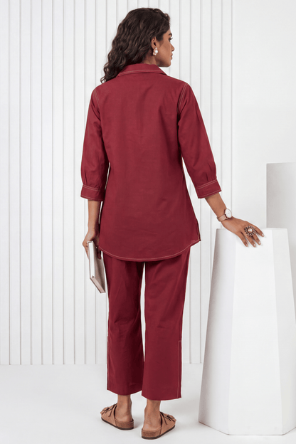 Woman wearing a maroon outfit standing against a white background