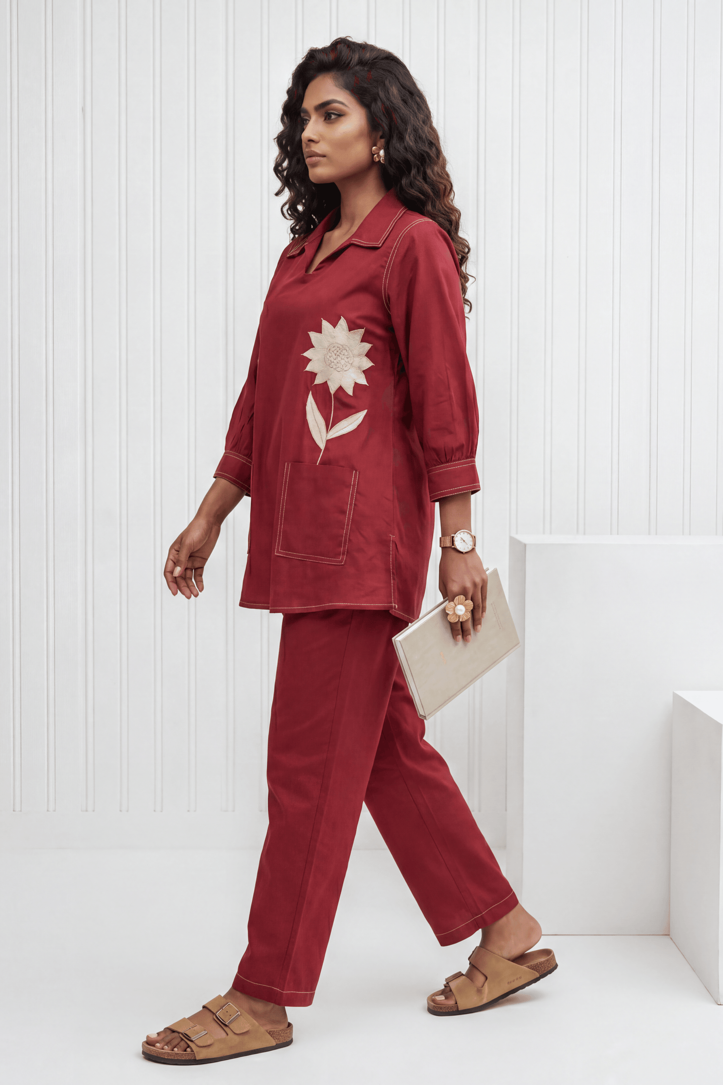 Woman wearing a red outfit with a floral design, standing against a white background