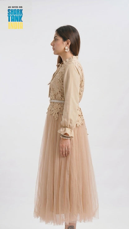 Woman wearing a beige lace dress with a plain background
