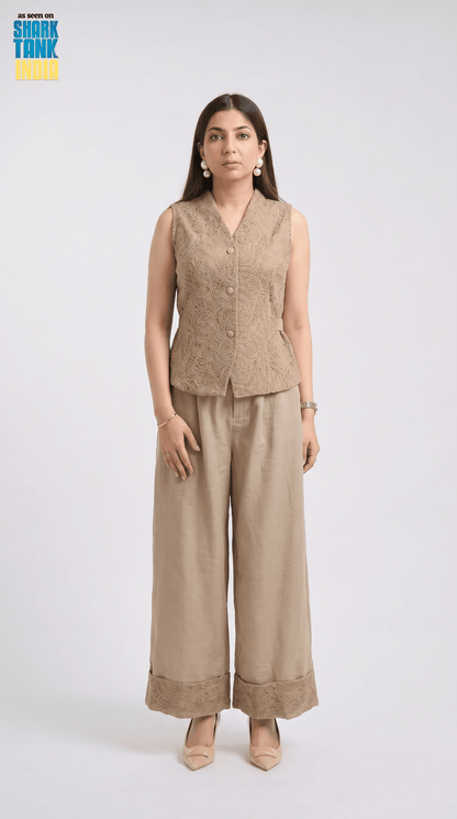 Woman wearing a beige sleeveless top and wide-leg pants on a white background
