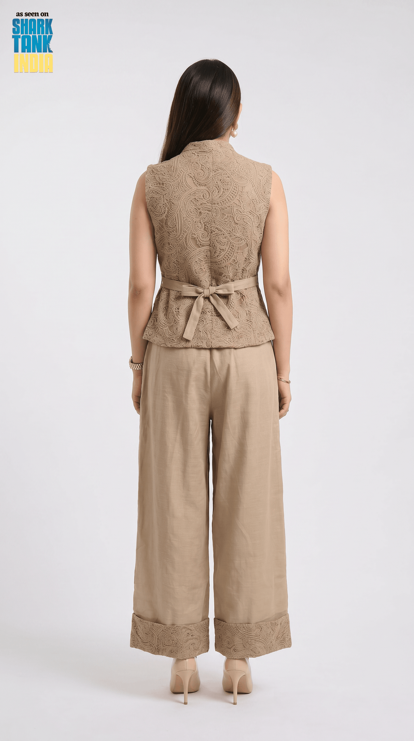 Woman wearing a beige sleeveless top and wide-leg pants on a white background