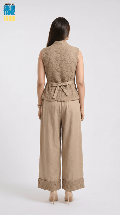 Woman wearing a beige sleeveless top and wide-leg pants on a white background