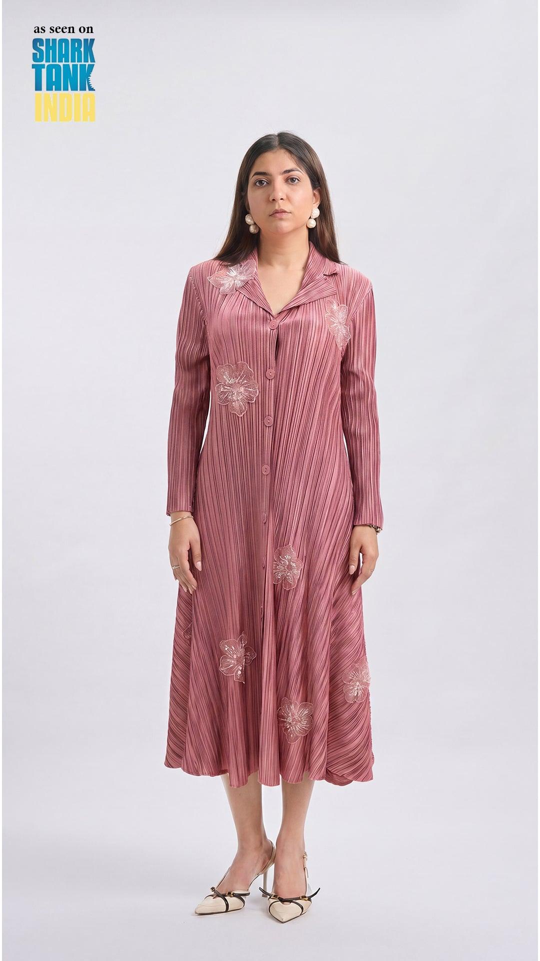 Woman wearing a pink dress with floral patterns on a white background, featuring 'Shark Tank India' branding.
