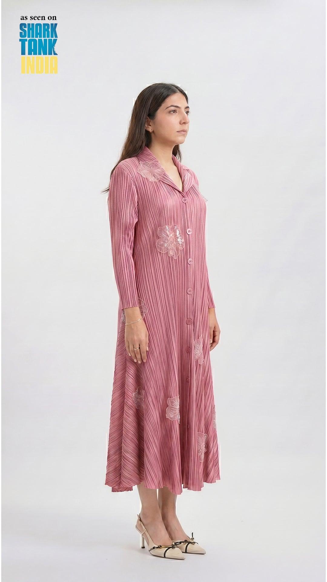 Woman wearing a pink dress with floral embroidery on a white background