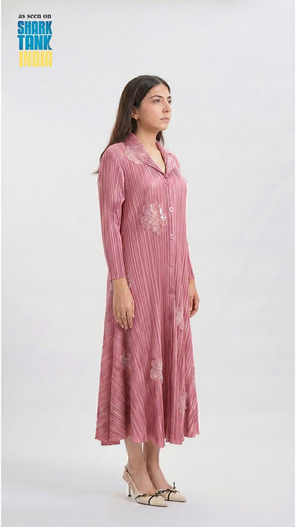 Woman wearing a pink dress with floral embroidery on a white background