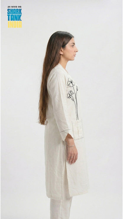 Woman wearing a white embroidered outfit on a plain background
