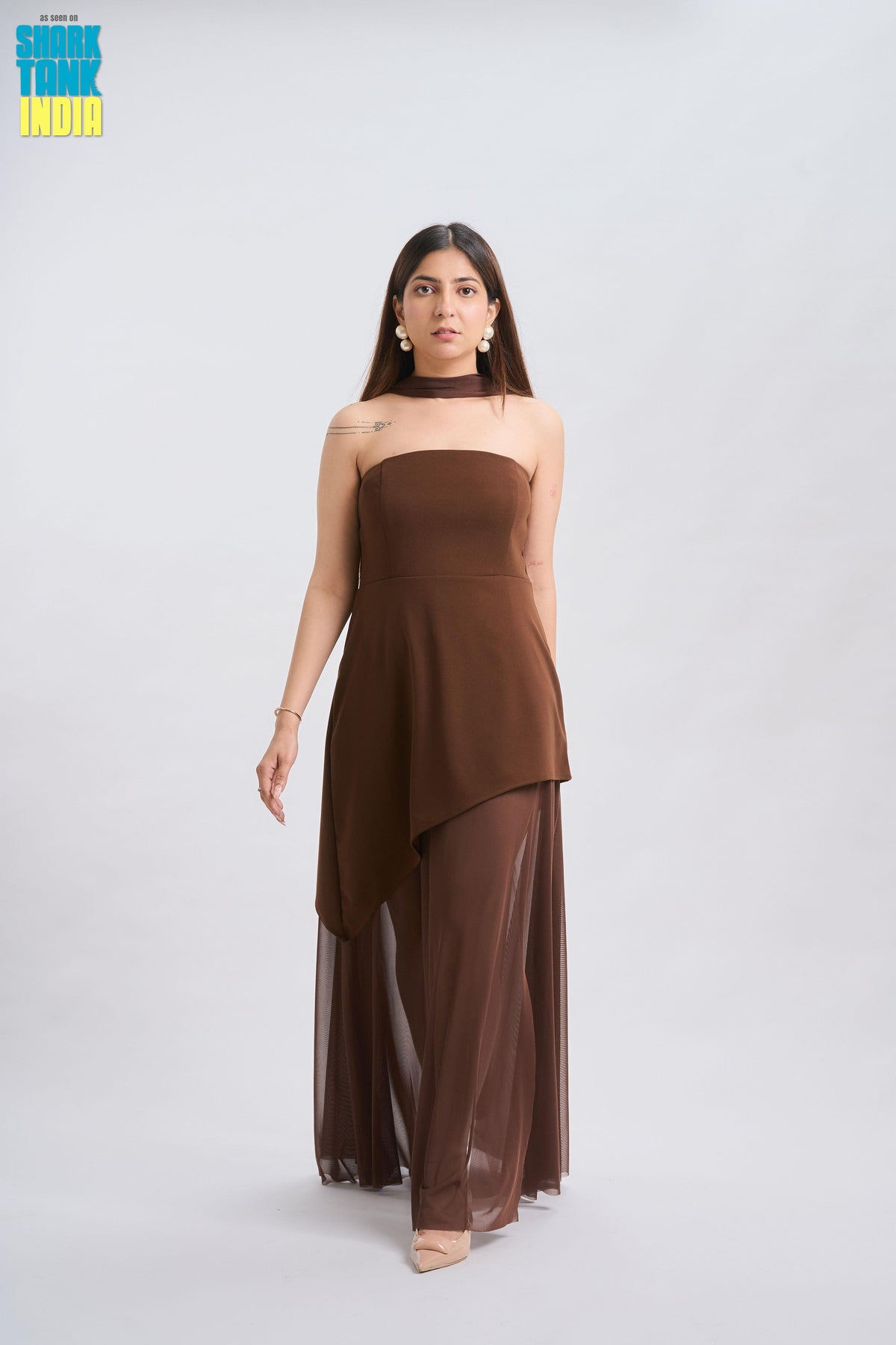 Woman wearing a brown strapless dress with sheer overlay on a white background