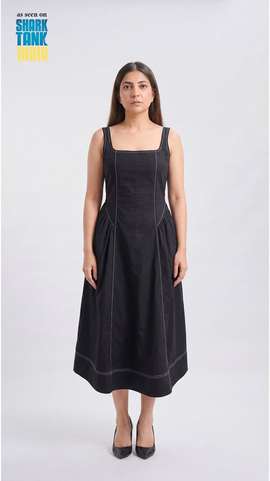 Woman wearing a black dress with white stitching on a white background
