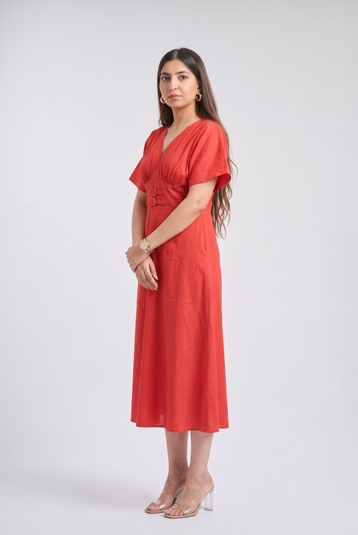 A woman modeling a red midi wrap dress with short flutter sleeves and a V-neckline, standing against a light gray studio background.