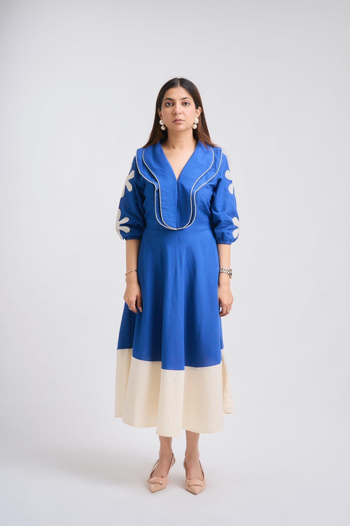 Woman wearing a blue dress with white accents on a white background
