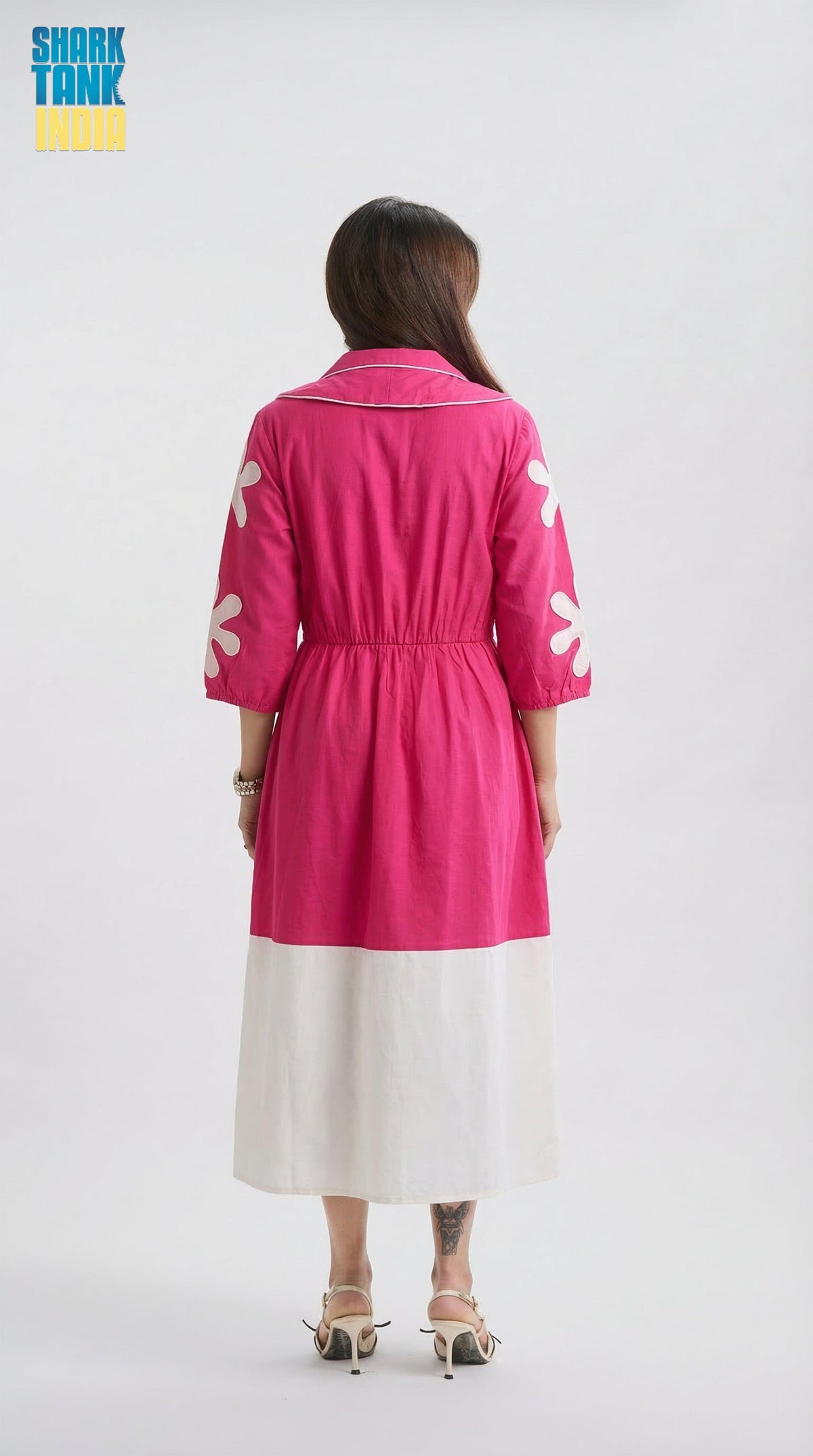 Person wearing a pink dress with white patterns on a white background