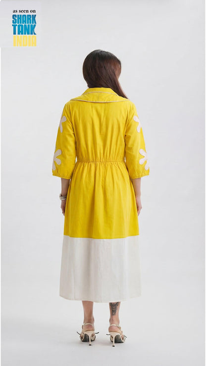 Woman wearing a yellow dress with white polka dots on a plain background