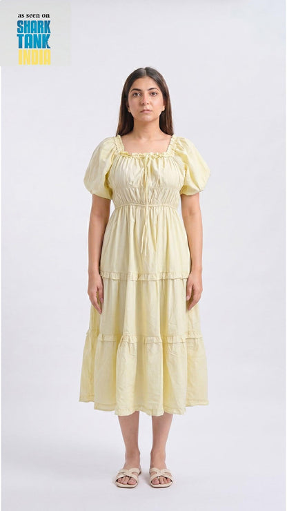 Woman wearing a light yellow dress on a white background with 'Shark Tank' branding.