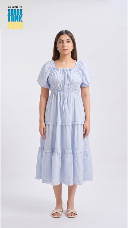 Woman wearing a light blue tiered dress on a white background with 'Shark Tank' branding.